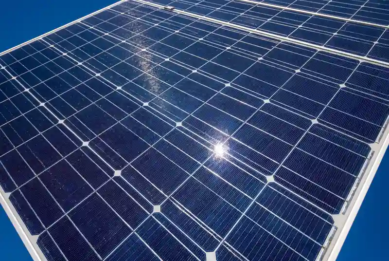 Gros plan de panneaux solaires en plein midi avec lumière naturelle intense et reflets lumineux